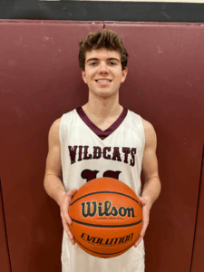 Jack Jenkins wearing a white Wildcats basketball jersey holding a Wilson basketball